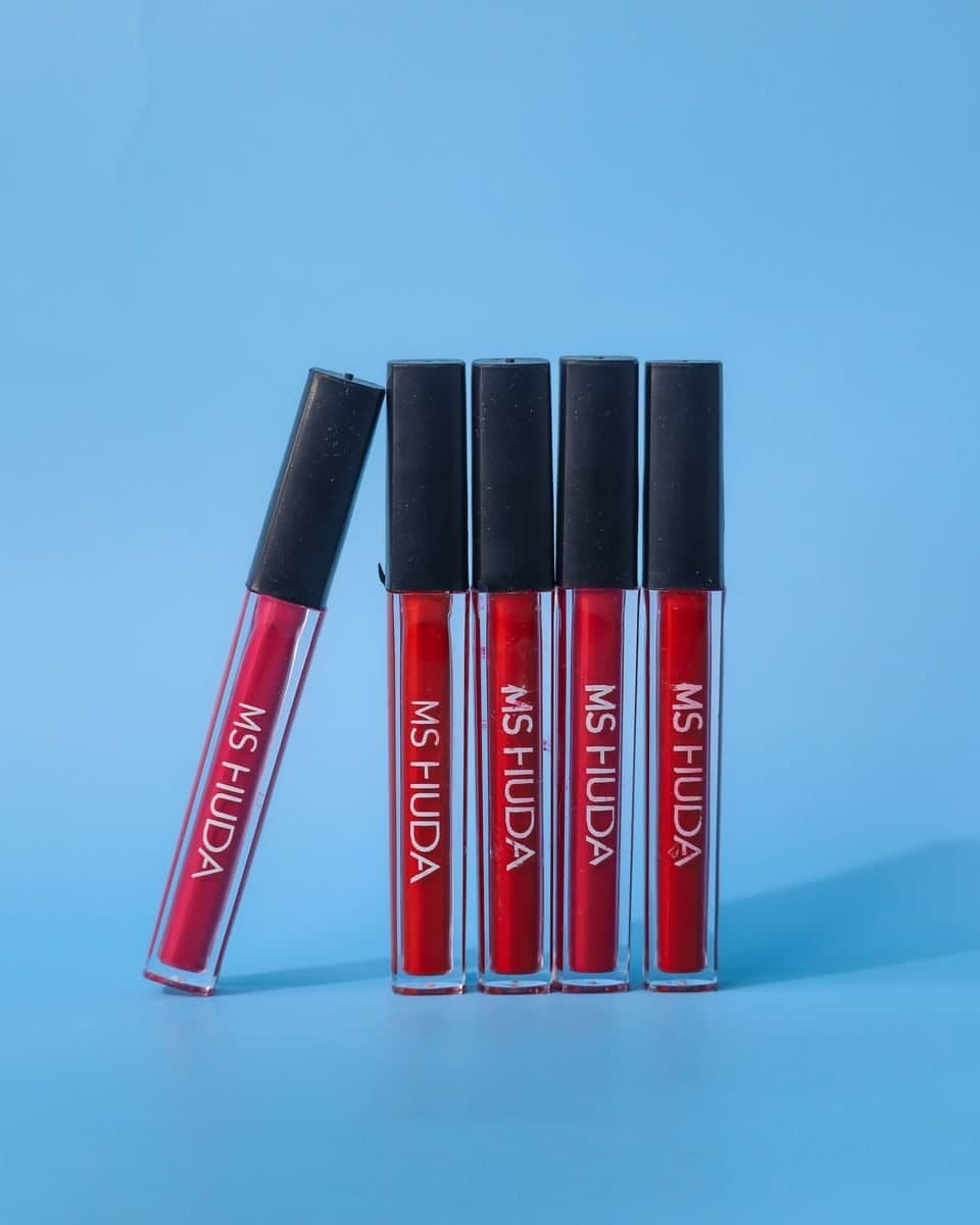 Five red lipstick tubes displayed on a vibrant blue background.